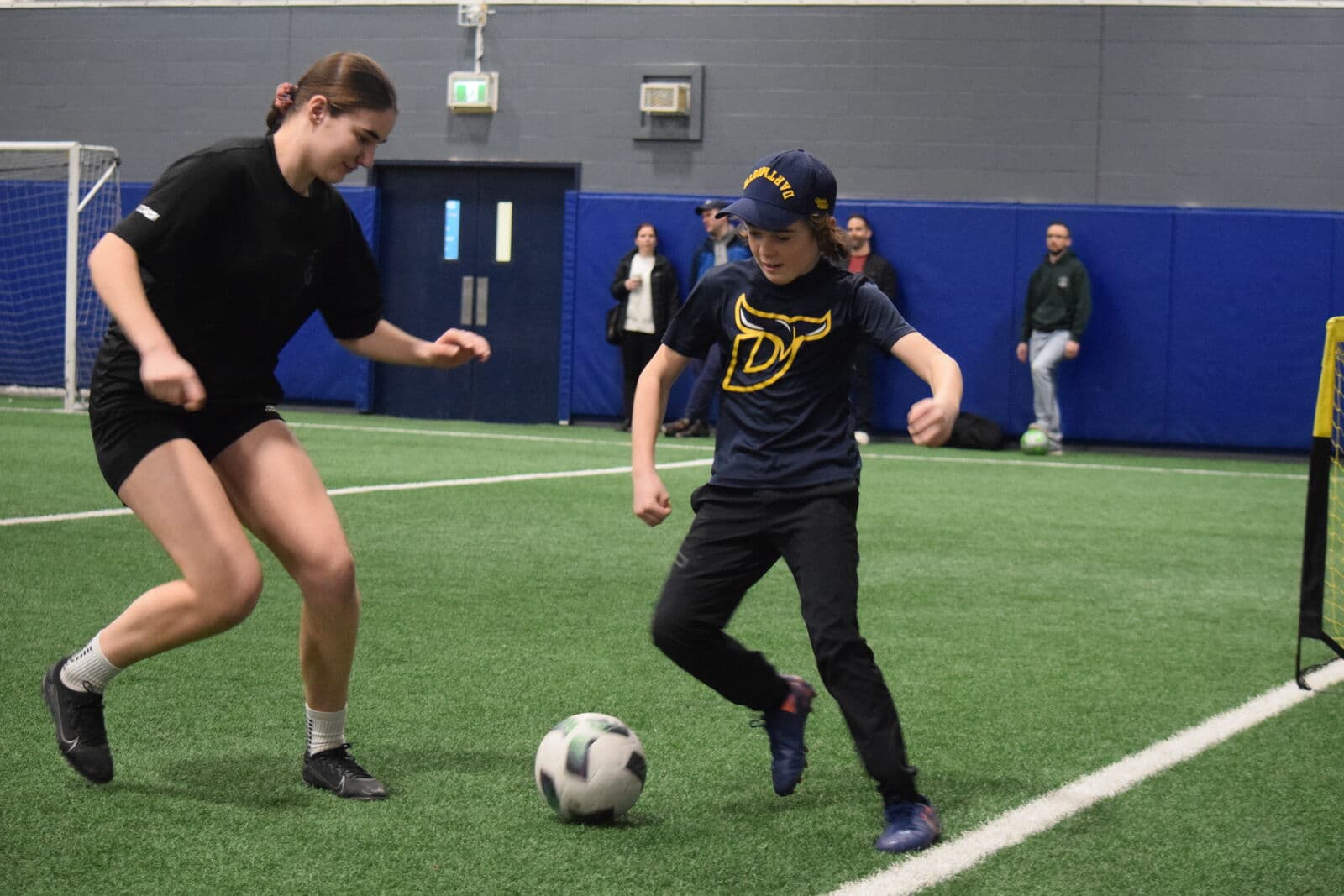 Goalkeeper coach Addison Graves guiding a 1-on-1 dribbling battle on the pitch.