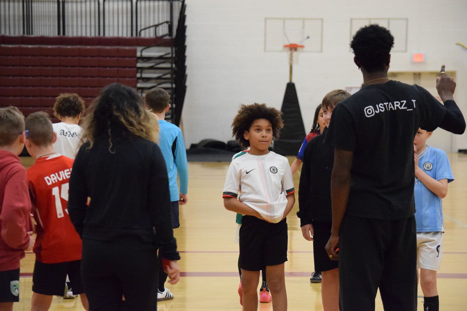 A JStarz coach guiding players through a drill in the gym.