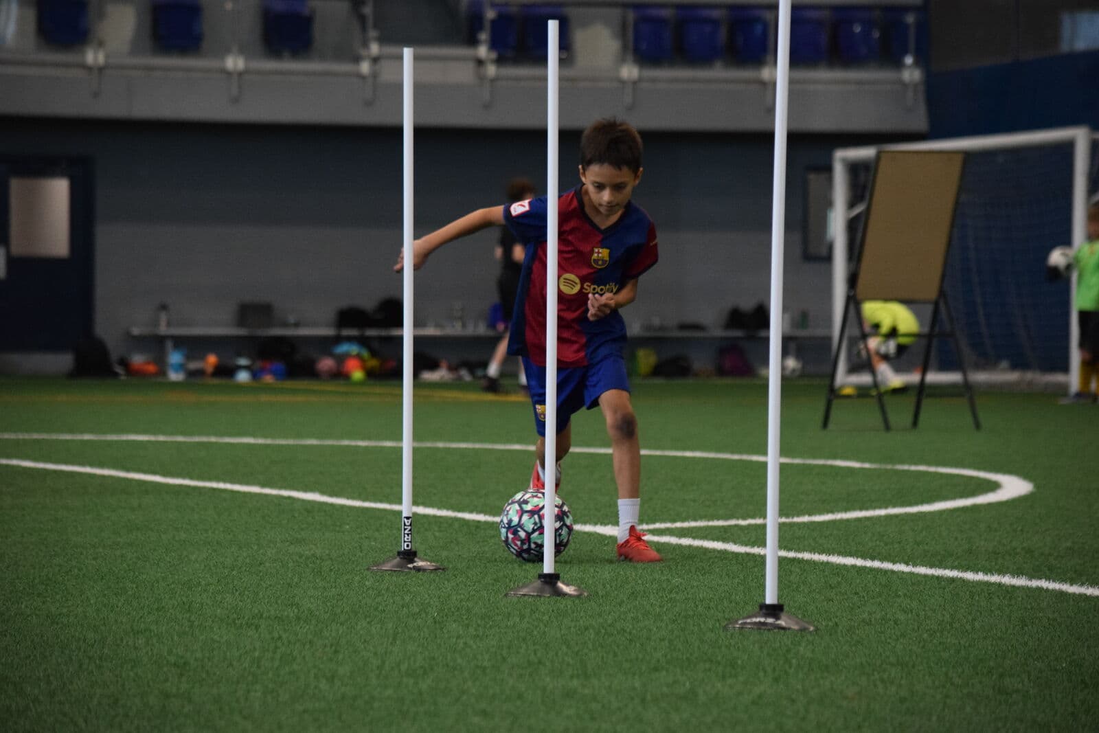 A young JStarz player dribbling through slalom poles during technical training.