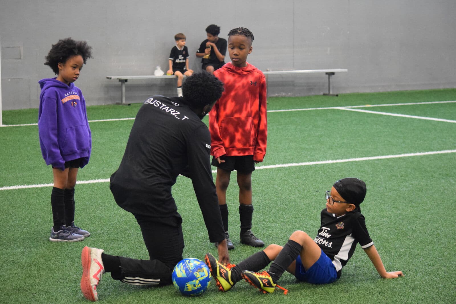 A coach working closely with a young player between drills.